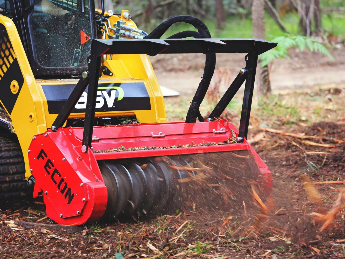 Fecon mulcher working through brush on a tracked loader.