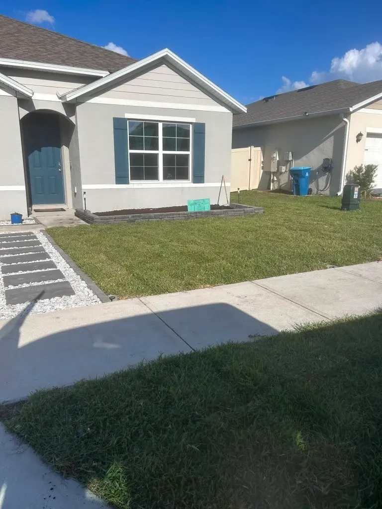 Front yard before landscaping, with an empty planting bed beneath the front window.