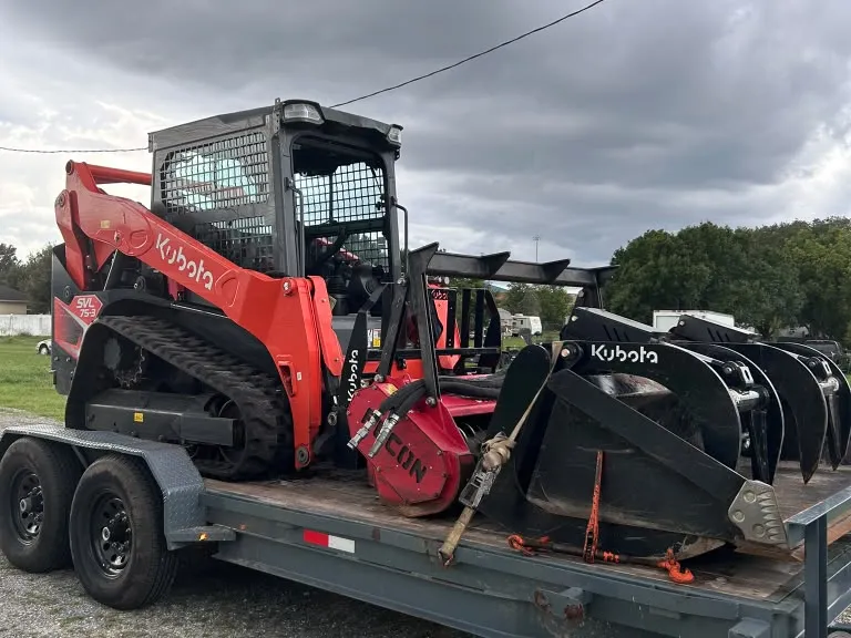Kubota SVL75-3 and attachments secured on a transport trailer.